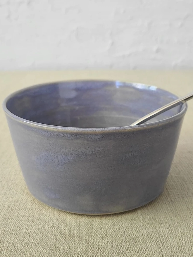 Classic Ceramic Breakfast Bowl, a breakfast bowl sitting on a grey carpet against a plain backdrop. It is accompanied by some cereal and a spoon. 