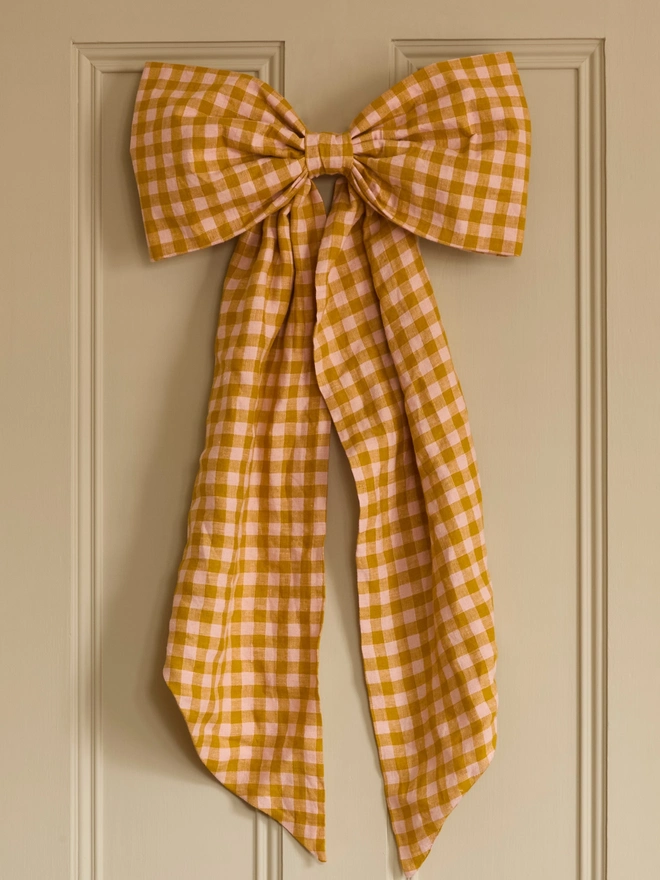 Handmade peach and mustard gingham linen door bow on interior door, close up, Kika Bespoke