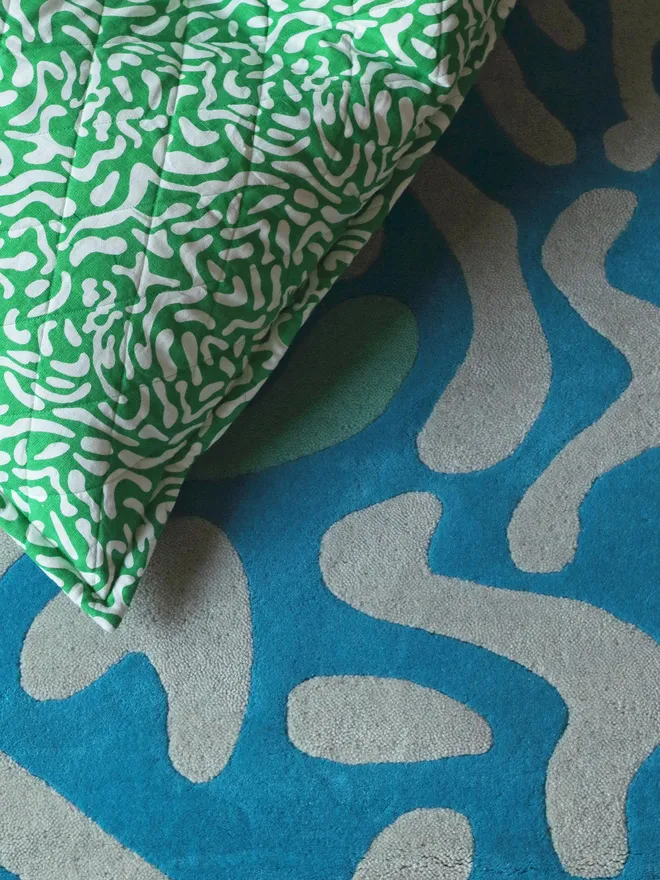 Lagoon Hand Tufted Rug, a blue rug on the floor with a colourful green bean bag sitting on top.