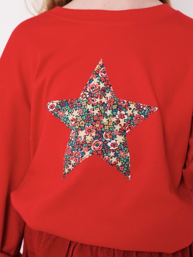 a 5 year old girl wearing a red t-shirt with a floral Liberty star shape on the front.