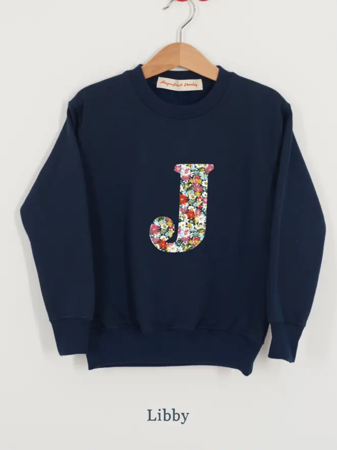 a navy kids sweatshirt with the initial J personalised in floral liberty print on the front