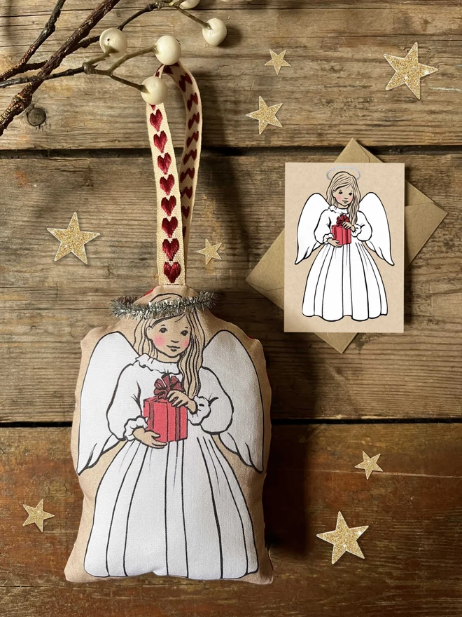 an angel christmas tree decoration made from printed fabric stuffed with plusf filler with a tinsel halo heart ribbon and mini matching greeting card
