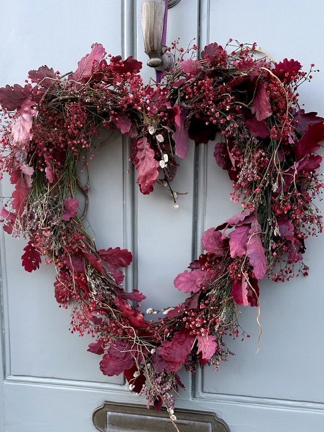 Dried Woodland Pink Heart Wreath hanging on a grey door