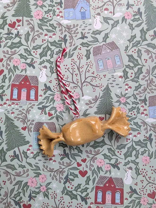 ceramic caramelle hanging christmas decoration. a small ceramic caramelle pasta ornament hanging from red and white thread.