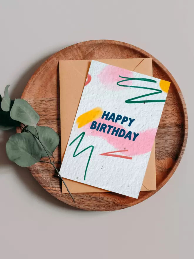 Happy Birthday Plantable Card Plantable Card with abstract pattern background on a wooden tray next to eucalyptus