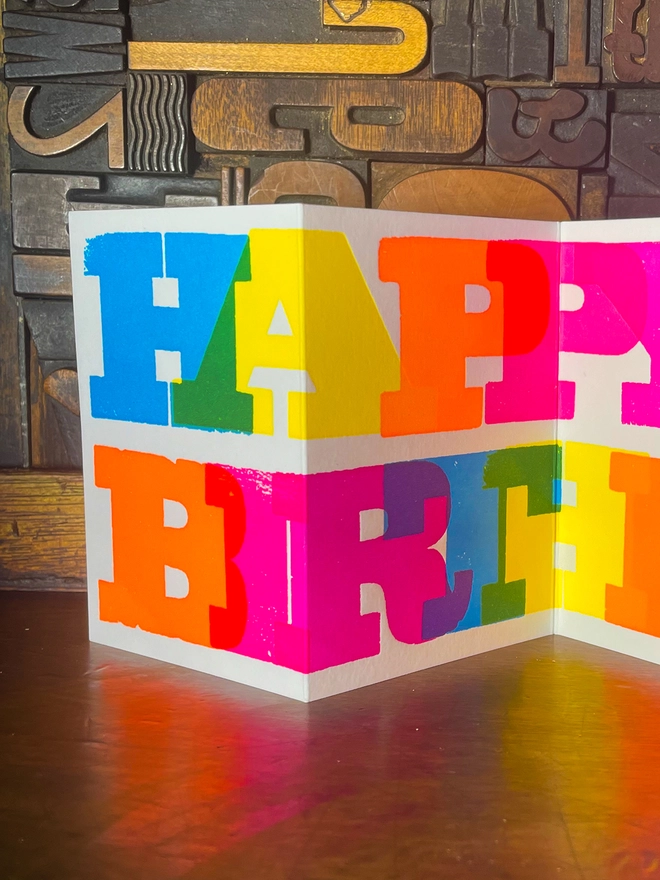 Artisan letterpress printed "Happy Birthday" concertina card featuring bold typography in six fluorescent inks with a deep impression print