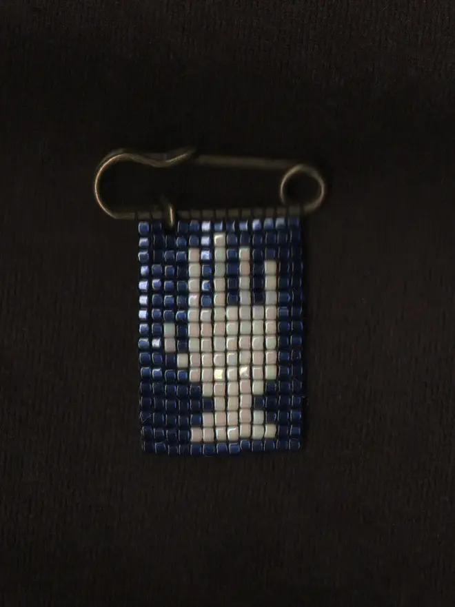 Tiled Beaded Hand Pin.  A beaded pin badge with a white hand on a blue background.