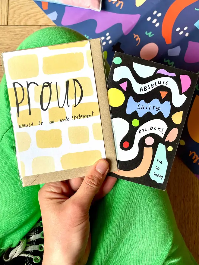 Nicola holds two of her cards against a colourful background