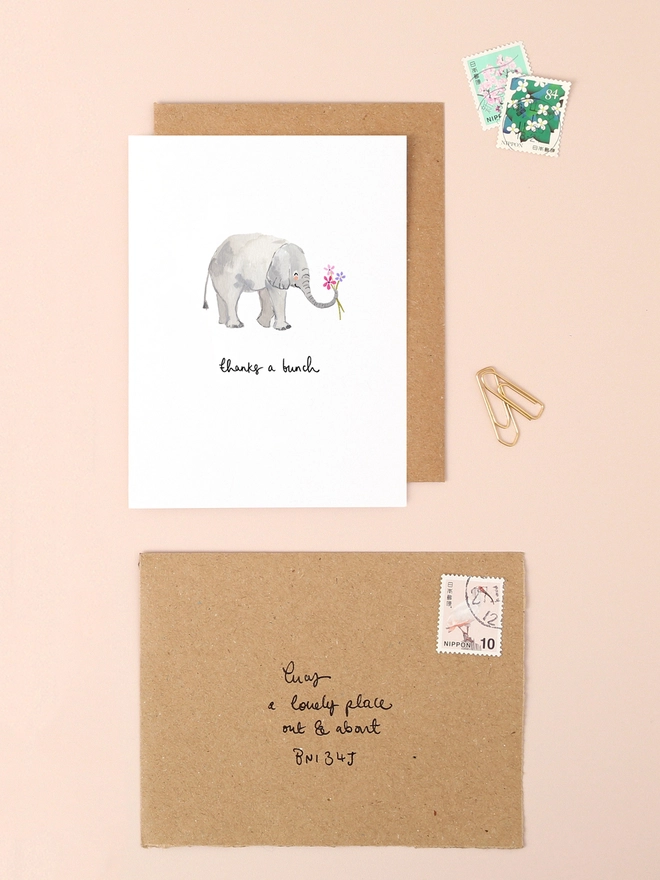 A delightful illustration of a cheerful elephant holding a vibrant bouquet of flowers in its trunk, conveying a heartfelt "thank you." The elephant's gentle expression and the colorful blooms add a touch of warmth and appreciation. The design is printed on textured, FSC-certified board, reflecting Louise Mulgrew's commitment to eco-friendly materials.