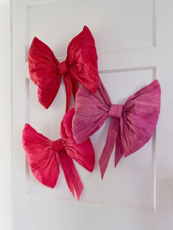 Crepe paper bowLarge crepe paper pink and red bows. Three large paper bows hung on a white door