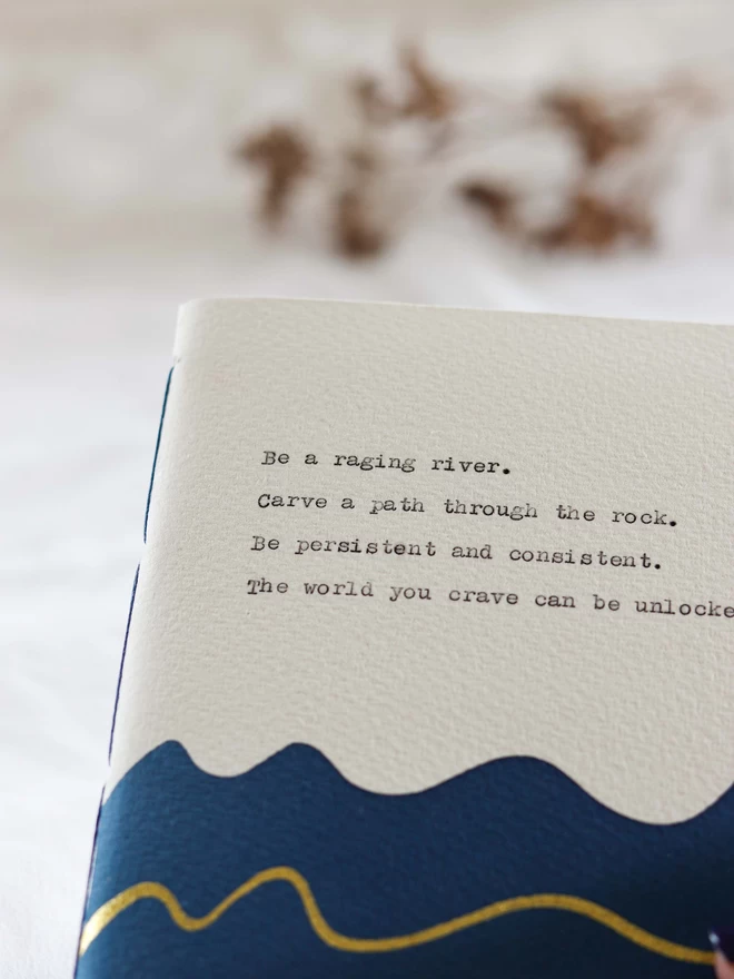 Close up of personalised typed text on Dark blue and white notebook with a gold wavy line