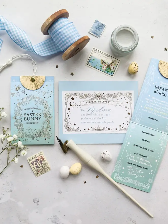 The pouch, addressed envelope and egg hunt card with its "hunt skill level" checkboxes. A gingham ribbon, a paint jar, stamps and speckled mini eggs are arranged around them.