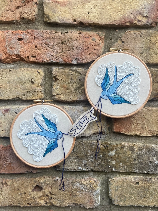 Embroidered swallows holding a banner in their beaks