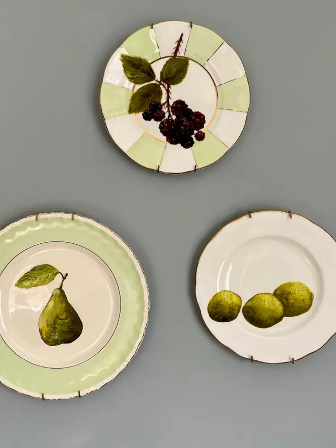 Fine Art Oil Painting Three Limes On A Vintage Plate, hanging on a grey wall with other paintings. 