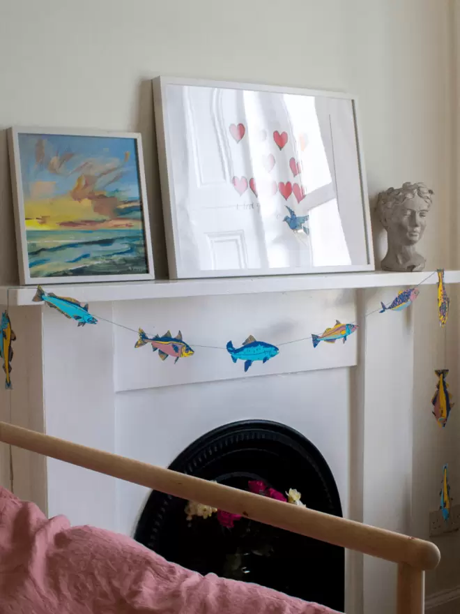 Multicoloured fish hanging over white fireplace 