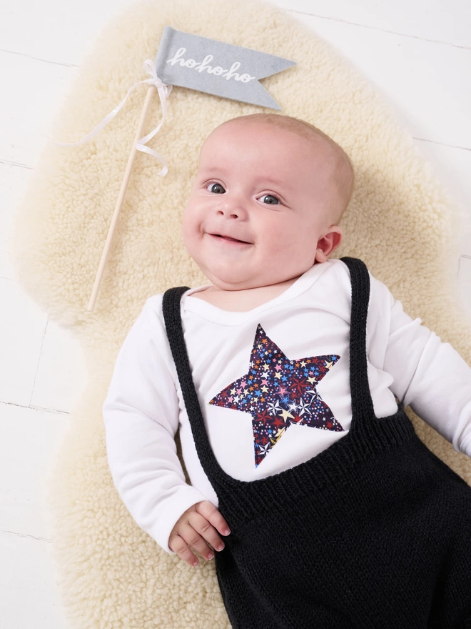 a baby wearing a liberty starry print star white bodysuit