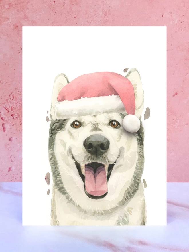 A Christmas card featuring a hand painted design of a siberian husky, stood upright on a marble surface. 
