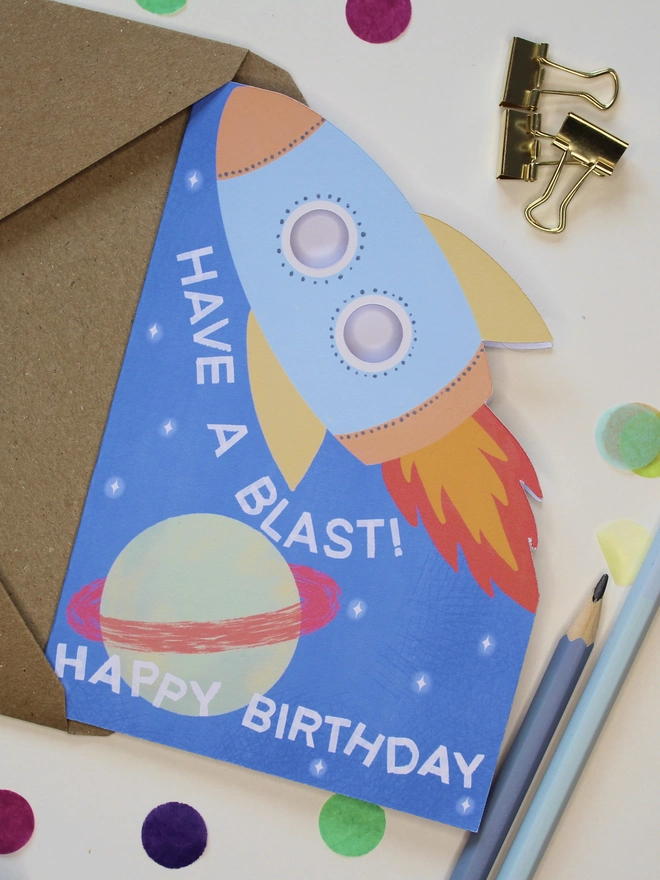have a blast rocket birthday card. blue card with illustrated rocket and planets.