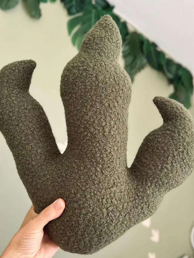 boucle dinosaur footprint cushion. a brown dinosaur foot cushion.