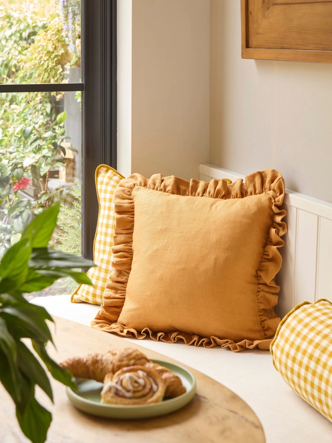 Handmade mustard classic linen ruffled cushion 45x45cm with feather pad on window seat, Kika Bespoke