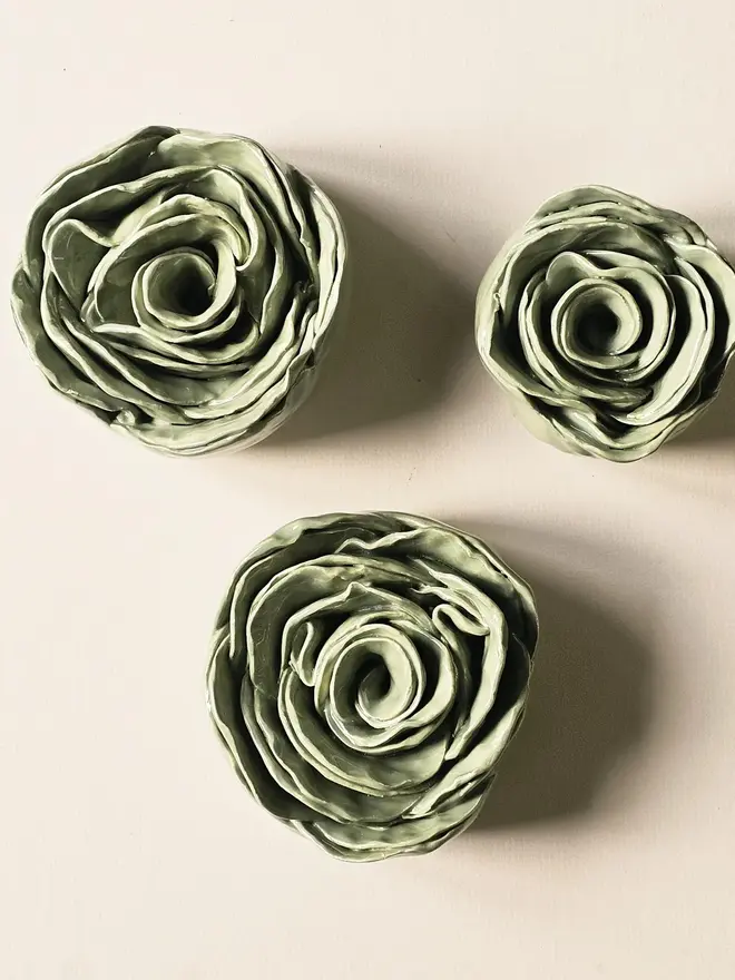 Handmade ceramic rose sculpture with a green glossy glaze, crafted in 3D and designed to hang on a wall