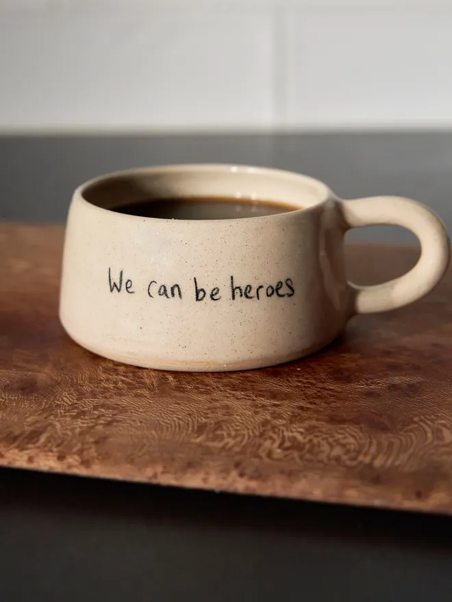 Cream ceramic mug with the words 'We Can Be Heroes' written on it 