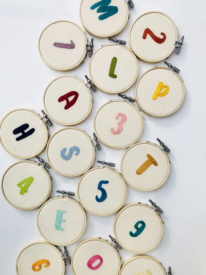 custom letter or number embroidered hoop. selection of cotton hoops embroidered with various letters and numbers in a variety of colours.