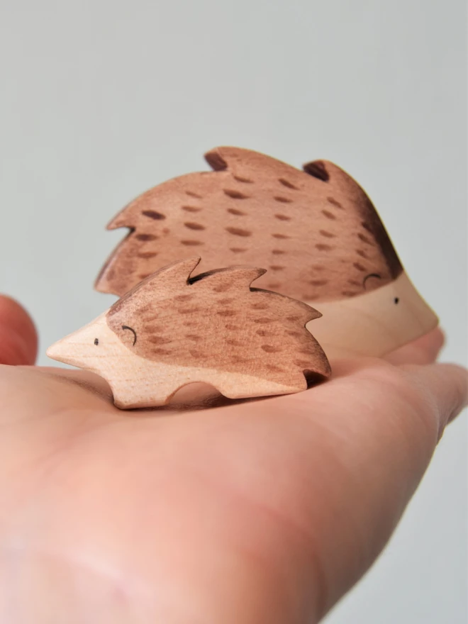 hedgehog and baby hoglet wooden toy on palm of hand