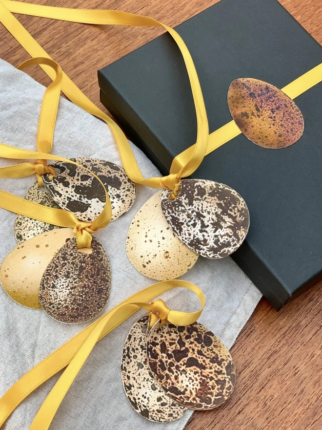 four pairs of speckled eggs tied with gold ribbon