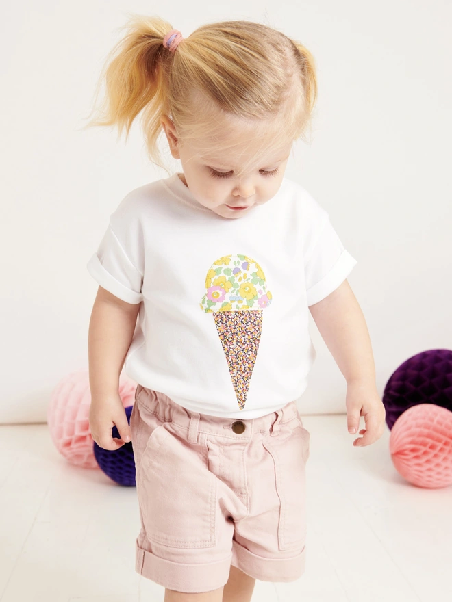 little girl wearing a white t-shirt with a floral ice cream sewn on the front