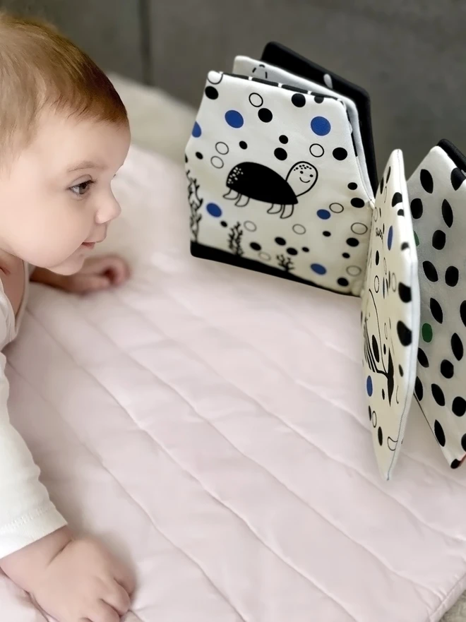 Baby during tummy time looking at My Quiet Book, High-contrast Soft Book