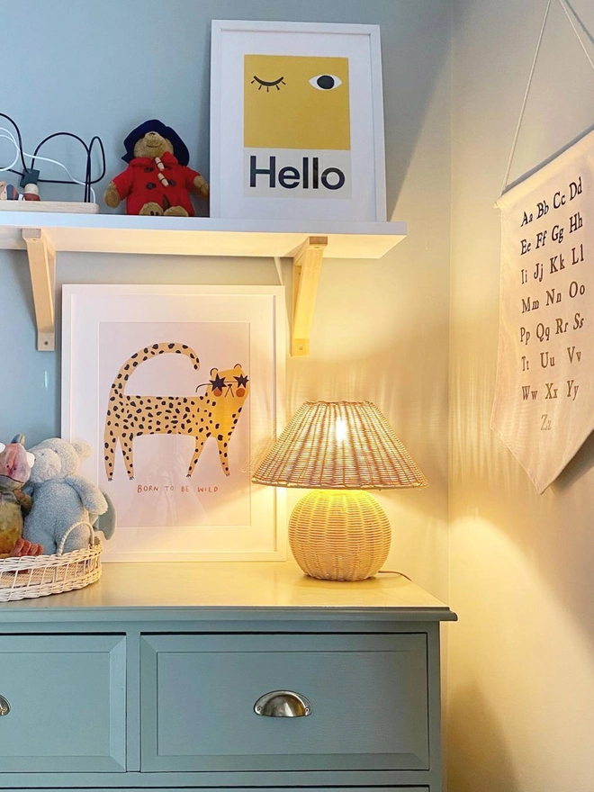 bold yellow wall print with word Hello hanging propped on a shelf in a nursery