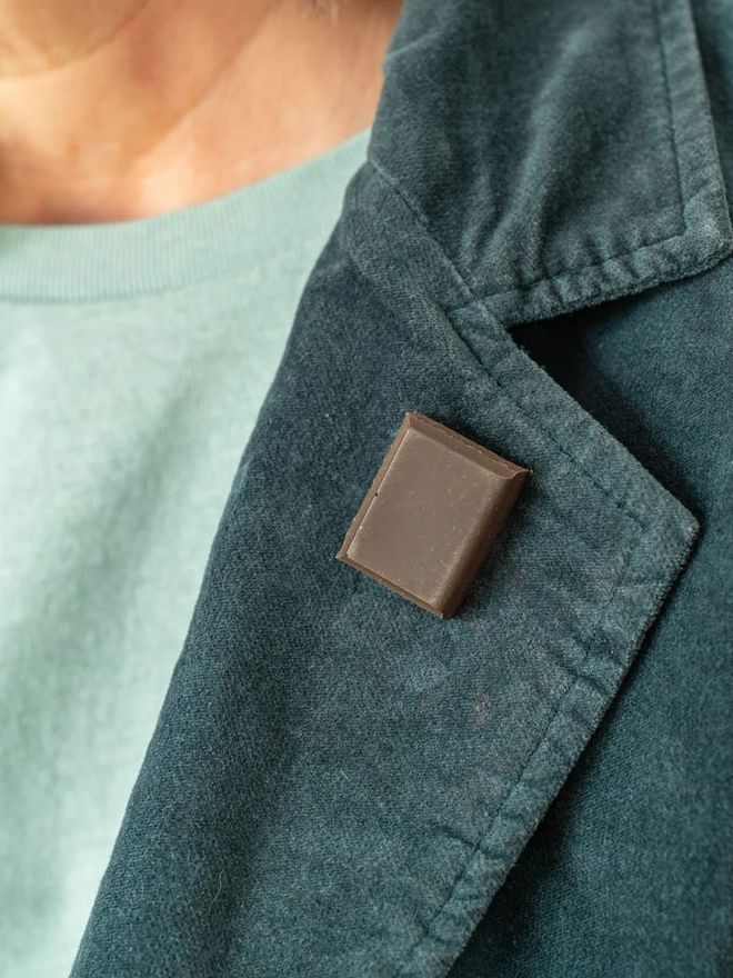 chocolate pin badges. a dark chocolate badge on a coat lapel.