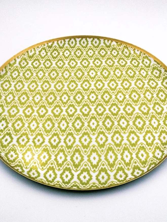 Large Enamel Circular Tray. A large round tray covered in lime green and white ikat-style print with a polished gold rim, shown on a white background. The bright geometric design makes a striking serving tray or decorative centrepiece.