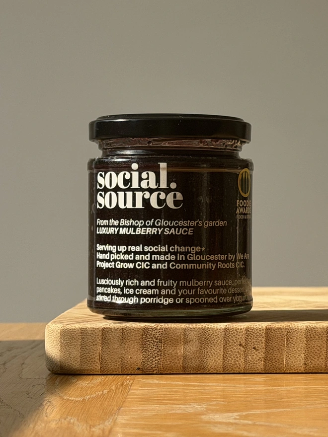jar of mulberry sauce on wooden chopping board
