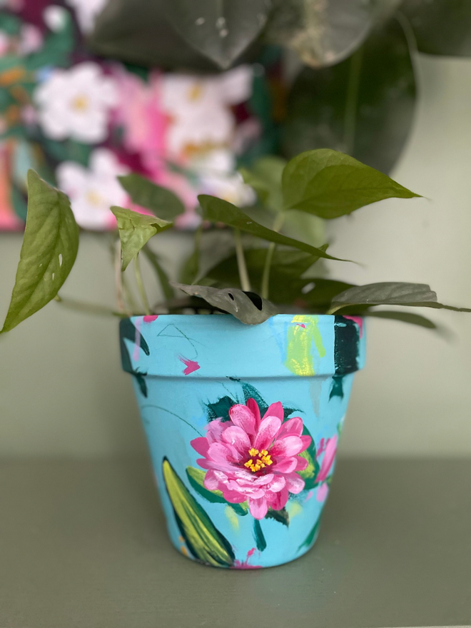 Hand painted floral pot in pale teal background bright pink zinnia flowers 