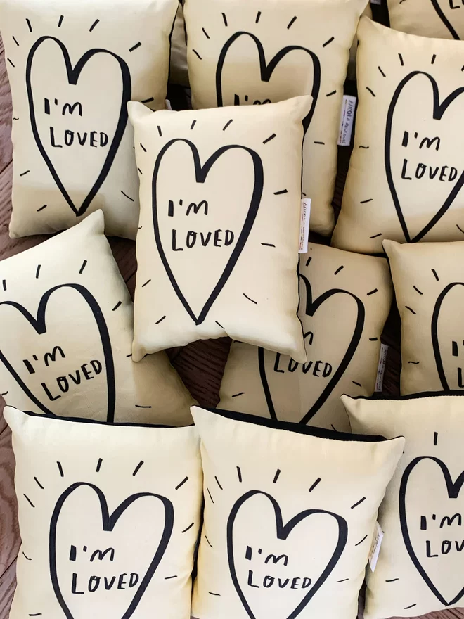A pile of mini plush pillows that say 'I'm Loved'