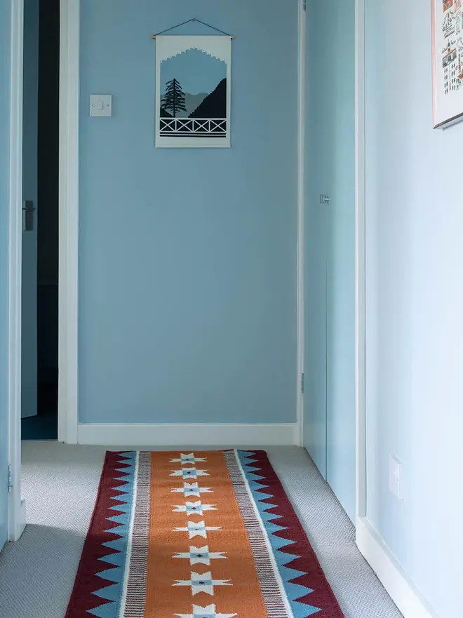 Victoria Flatweave Runner Rug, a colourful rug sitting in a decorated room. It is accompanied by other colourful household items. 