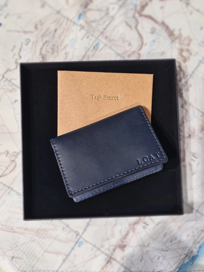a personalised blind embossed navy blue leather card wallet lined with a rare historical silk war map in a black gift box by Natthakur