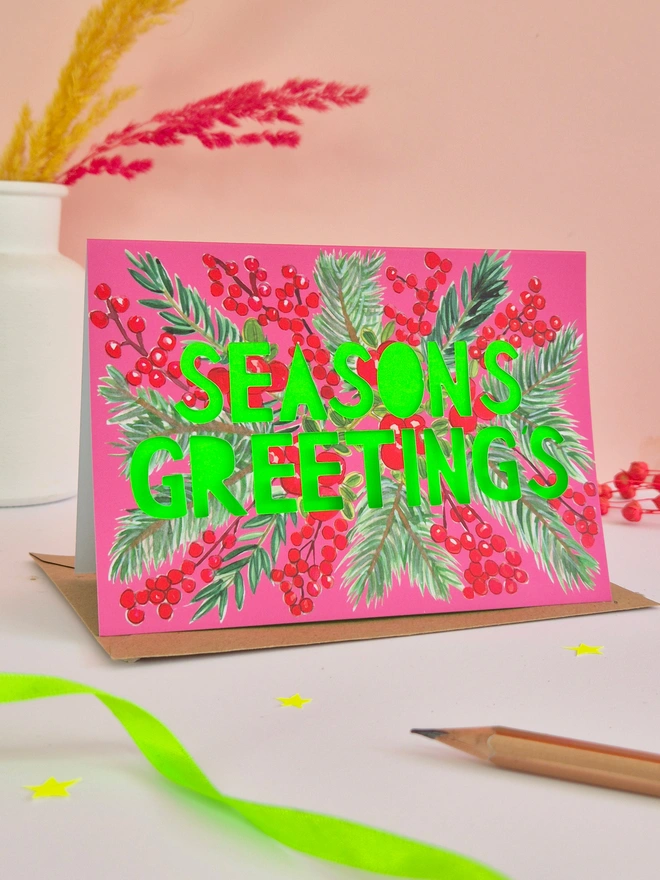 Cranberry design Christmas Card with Seasons greetings in paper cut text and a neon green backing paper 