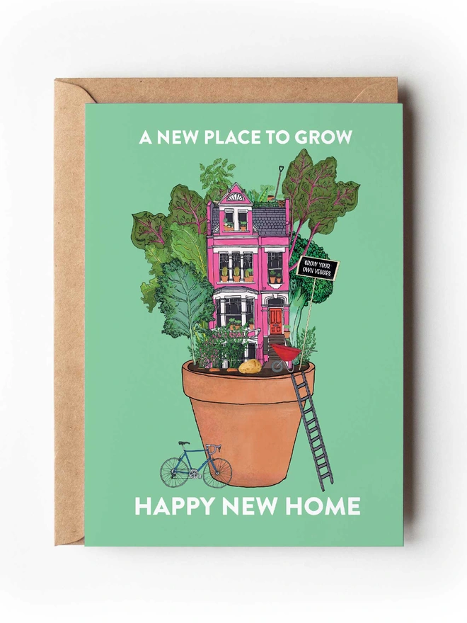 Food-inspired illustrated greeting card featuring a pink house in a pot surrounded by vegetables, set against a green background. 