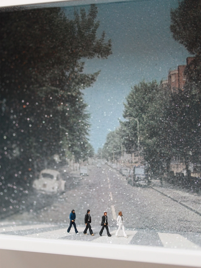 Miniature scene in an artbox showing four tiny Beatles - John Lennon, Paul McCarthney, Ringo Starr and George Harrison walking across the famous pedestrian crossing from the album Abbey Rd