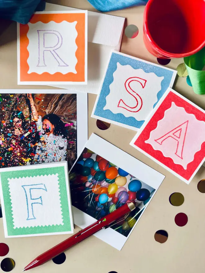 Hand printed mini letter Cards on a table with scattered confetti. 