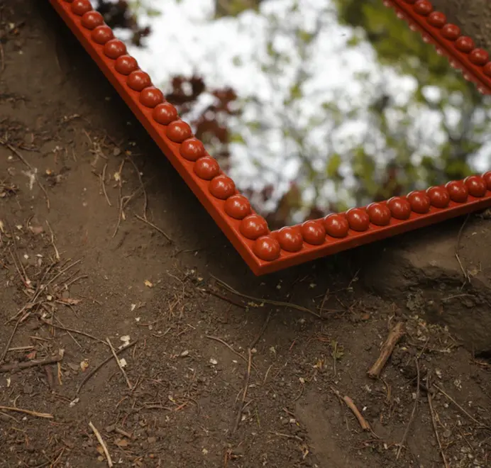 Floor-length bobbin mirror with a turned wooden frame, leaning against a wall on a concrete floor.
