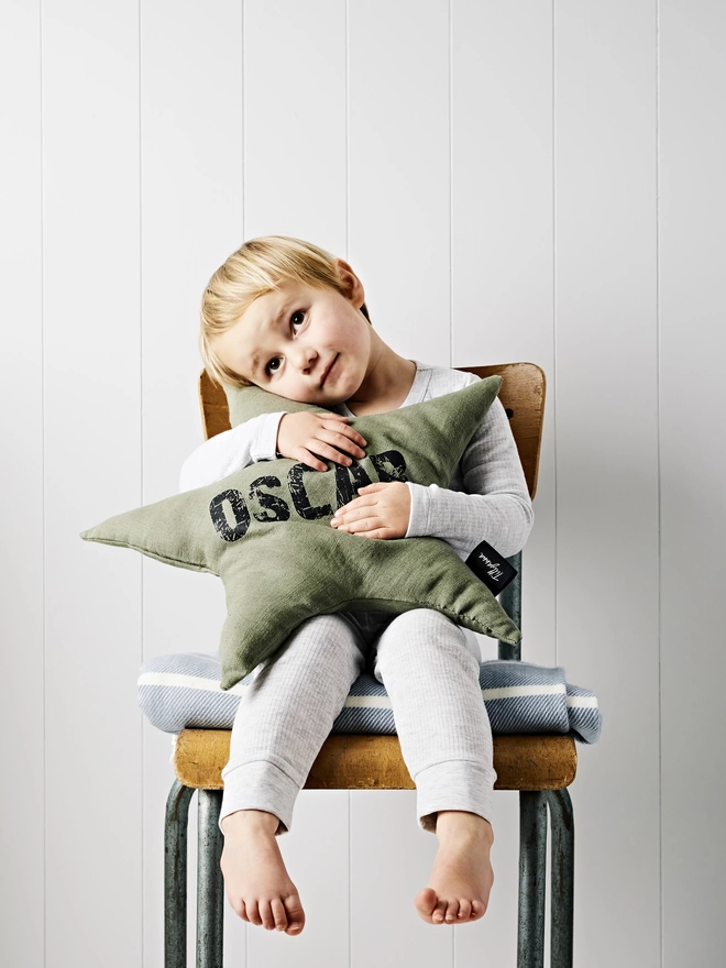 Personalised star shaped linen cushion being hugged by child