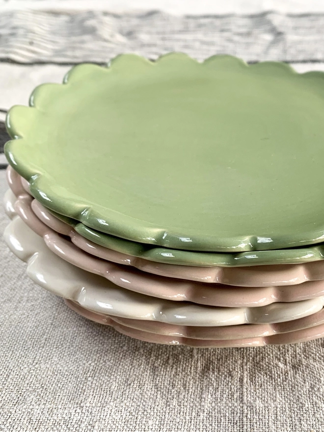 stack of medium size camellia scallop edge side plates in sage green, pale pink and white
