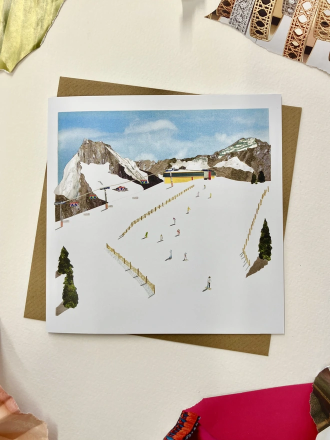 Christmas card featuring a collage of a ski slope on a white background with collage papers 
