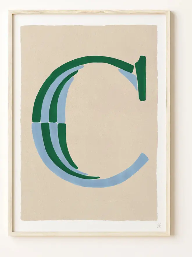 Framed wall art print featuring a large decorative letter “C” in humbug stripes
centered on a white background. 