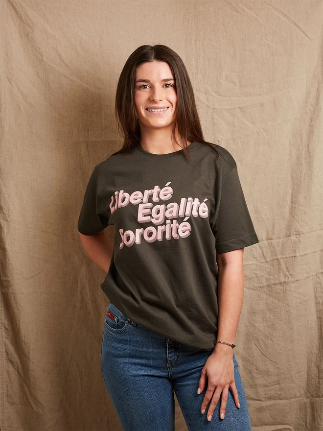 Model is wearing a charcoal grey cotton t-shirt with the slogan Liberté, Egalité, Sororité in pale pink written on the front