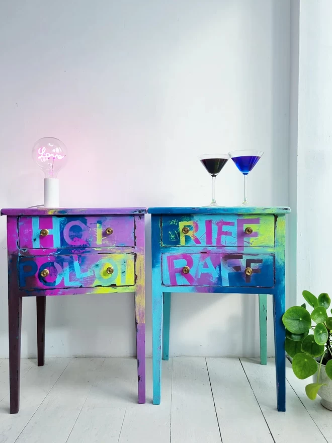 Pair of painted bedside tables or drawers in graffiti distressed style in neon yellow, teal, purple, pink. One says ‘riff raff’ and the other says ‘hoi polloi’